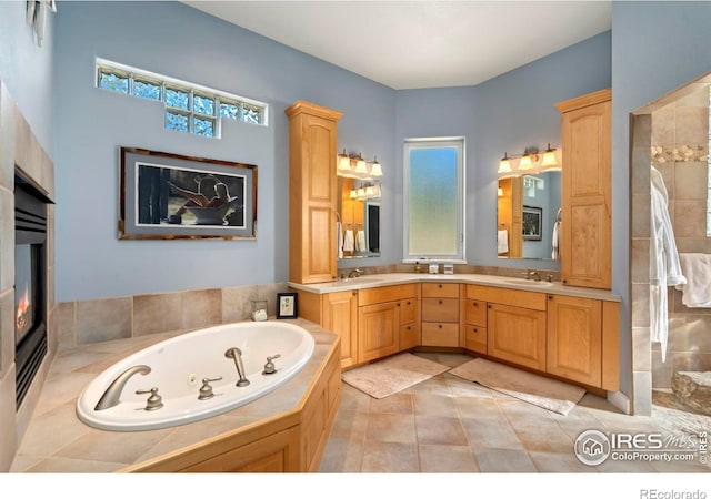 bathroom with a relaxing tiled tub, double vanity, and tile patterned flooring