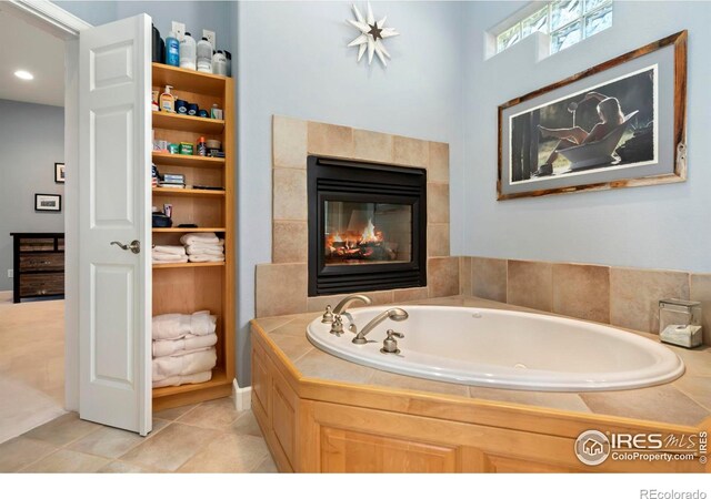 bathroom featuring tile patterned floors, tiled tub, and a fireplace