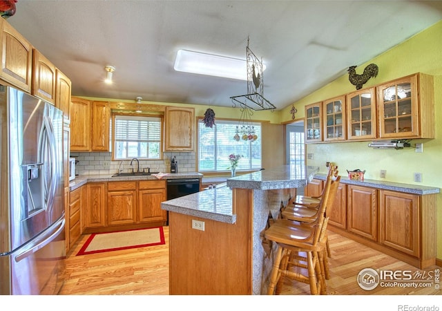 kitchen featuring stainless steel refrigerator with ice dispenser, light hardwood / wood-style floors, a breakfast bar, a kitchen island, and sink