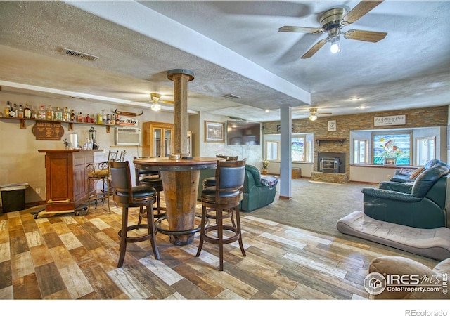 dining space featuring carpet, a textured ceiling, bar area, and ceiling fan