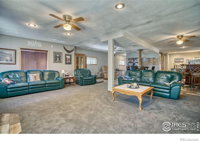 carpeted living room featuring ceiling fan and a textured ceiling