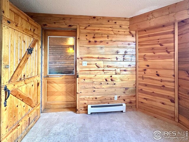 spare room with a textured ceiling, wooden walls, and a baseboard radiator