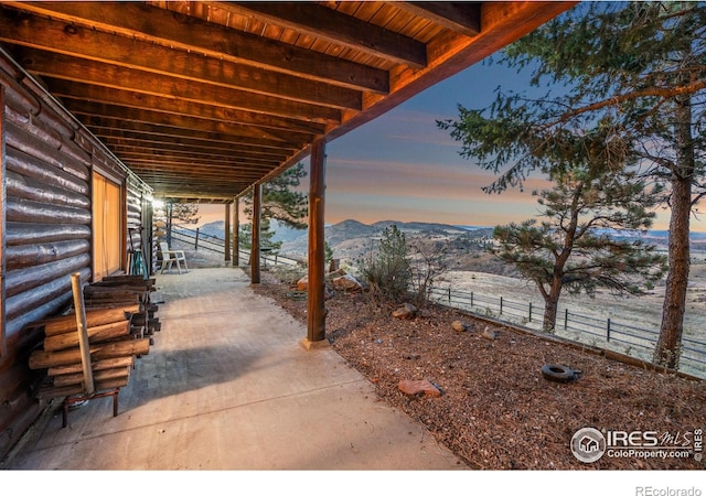 patio terrace at dusk with a mountain view and fence