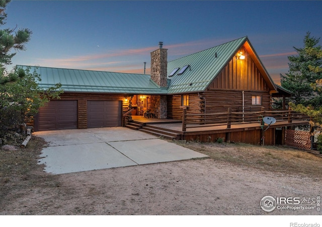 log home featuring driveway, a standing seam roof, a chimney, log exterior, and metal roof