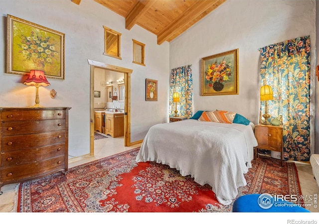 bedroom with tile patterned floors, ensuite bathroom, vaulted ceiling with beams, and wood ceiling