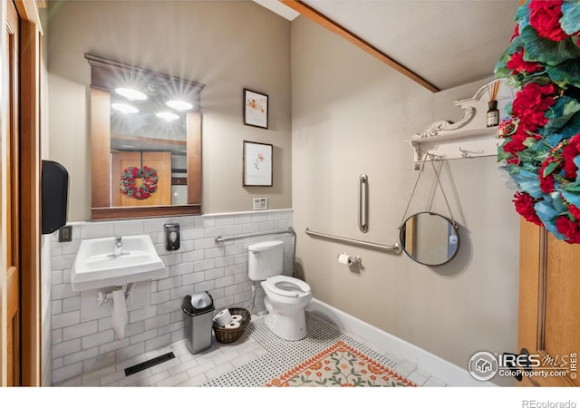 bathroom with tile patterned floors, toilet, sink, and tile walls