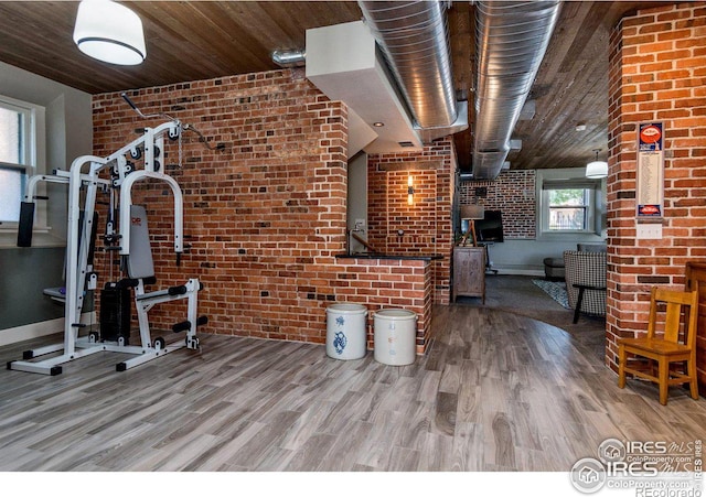 workout area featuring brick wall, hardwood / wood-style floors, and wood ceiling