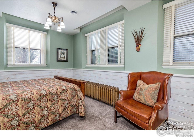 bedroom featuring an inviting chandelier, radiator, carpet flooring, and wood walls