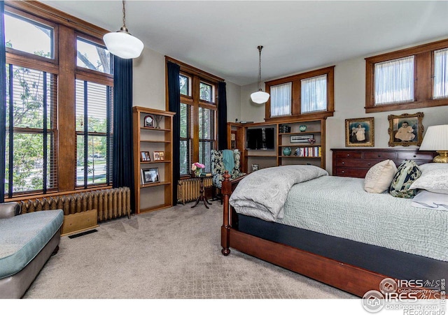 bedroom with light colored carpet and radiator