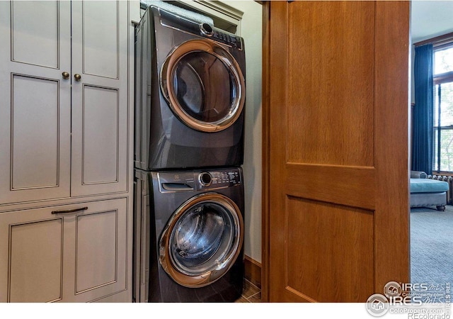 laundry room featuring stacked washer / dryer, carpet, and cabinets