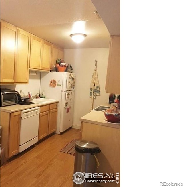 kitchen with light brown cabinets, light wood-type flooring, sink, and white appliances