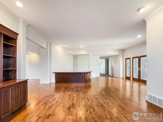 unfurnished living room featuring crown molding, light hardwood / wood-style floors, and french doors