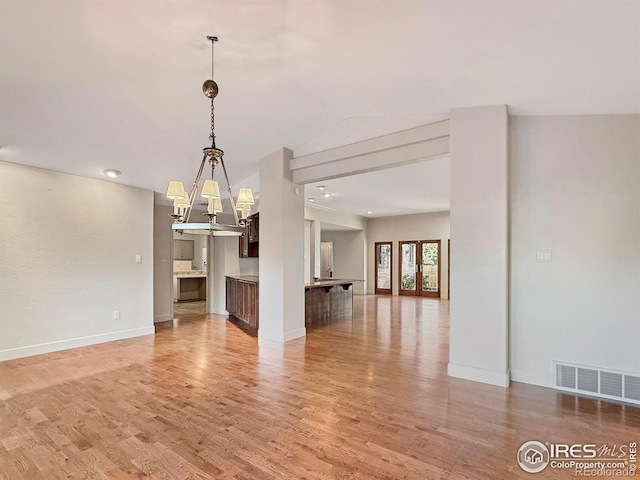 unfurnished living room with a chandelier and light hardwood / wood-style flooring