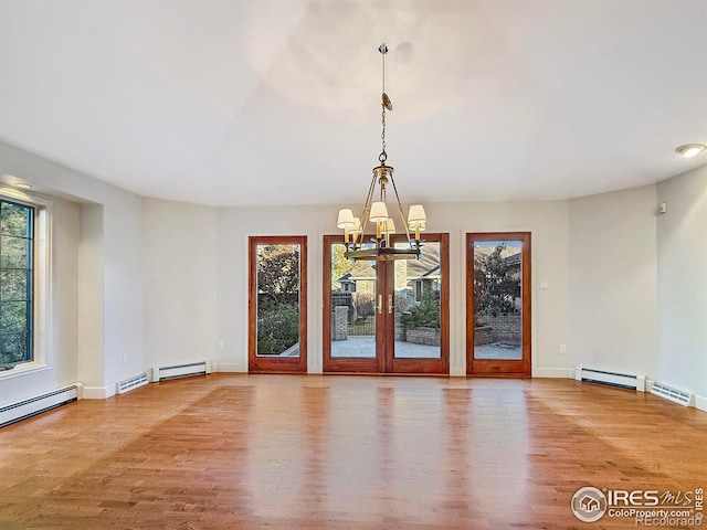 unfurnished room featuring hardwood / wood-style floors, a wealth of natural light, a chandelier, and baseboard heating