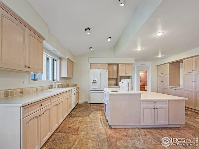 kitchen featuring sink, vaulted ceiling, light brown cabinets, a kitchen island, and white appliances