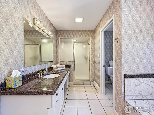 bathroom with a baseboard heating unit, vanity, a shower with shower door, tile patterned floors, and toilet