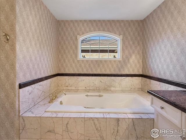 bathroom featuring vanity and tiled bath