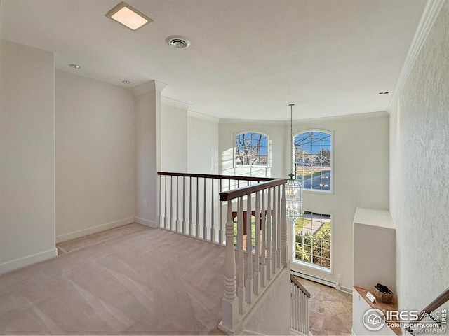 hall featuring an inviting chandelier, crown molding, and light colored carpet