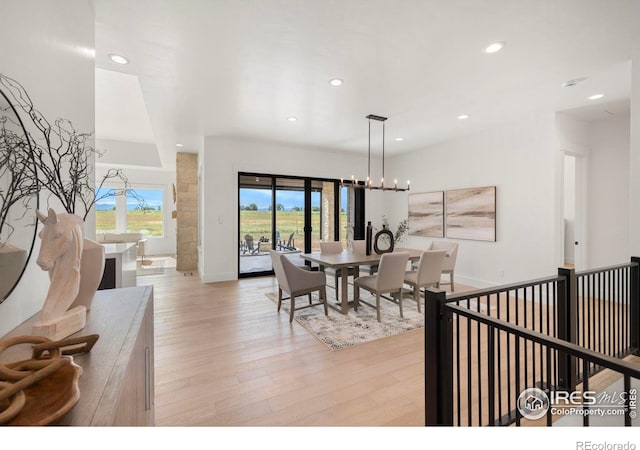 dining space with light hardwood / wood-style flooring and a chandelier