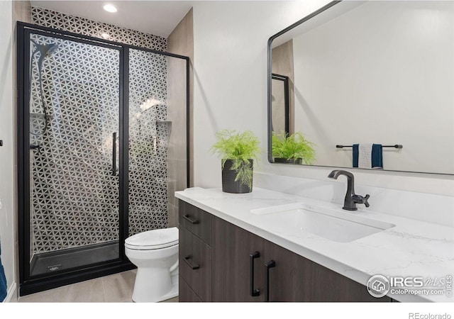 bathroom featuring a shower with door, toilet, vanity, and hardwood / wood-style flooring