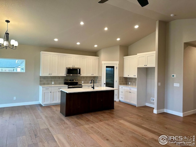 3274 Buffalo Grass Ln, Wellington, CO 80549 - kitchen featuring stainless steel appliances, light countertops, an island with sink, tasteful backsplash, and white cabinetry
