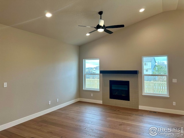 unfurnished living room featuring lofted ceiling, a fireplace, ceiling fan, and a healthy amount of sunlight