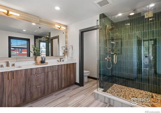 bathroom featuring dual vanity, tile patterned floors, toilet, and a shower with door