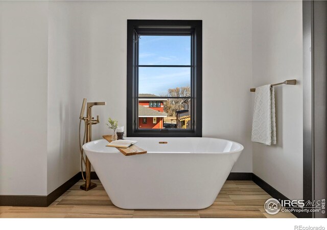 bathroom with a bathing tub and hardwood / wood-style flooring