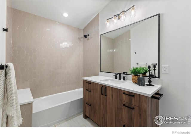 bathroom featuring tiled shower / bath combo, tile patterned flooring, and vanity