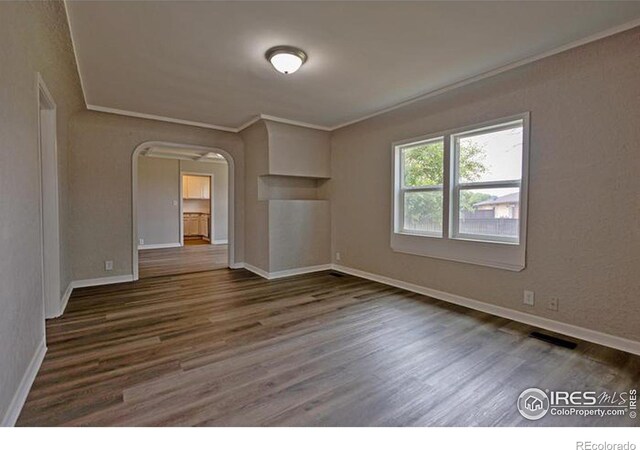 unfurnished room with dark wood-type flooring and crown molding