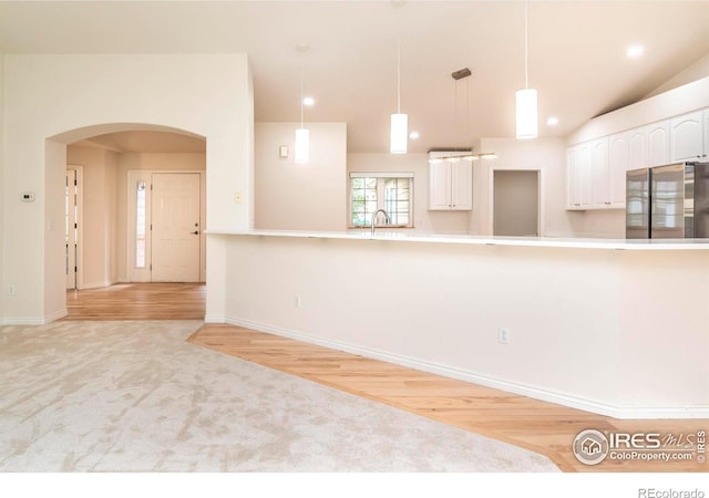 kitchen with light carpet, white cabinets, hanging light fixtures, light countertops, and freestanding refrigerator