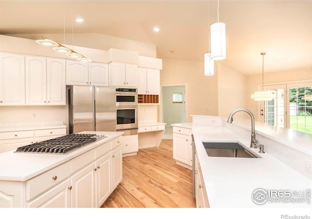 kitchen with appliances with stainless steel finishes, light countertops, a sink, and decorative light fixtures