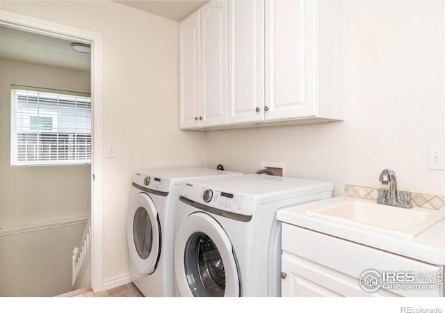 washroom featuring cabinet space, a sink, and washing machine and clothes dryer