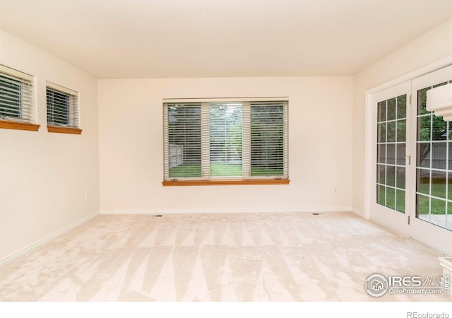 unfurnished room featuring baseboards and light colored carpet