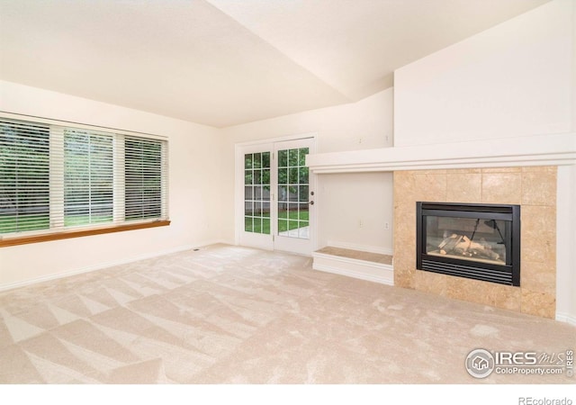 unfurnished living room with carpet floors, baseboards, lofted ceiling, and a tile fireplace