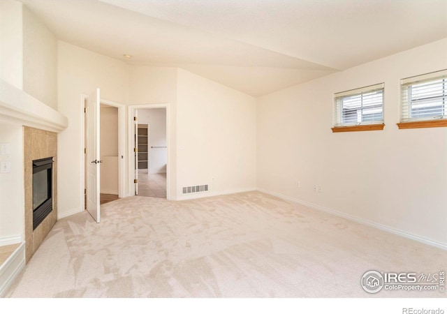 unfurnished living room with light colored carpet, a fireplace, visible vents, baseboards, and vaulted ceiling