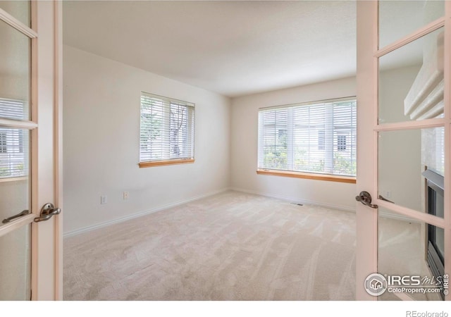 unfurnished room featuring light colored carpet and baseboards