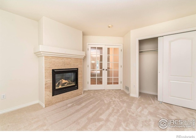 unfurnished living room with light carpet, french doors, a tile fireplace, and visible vents