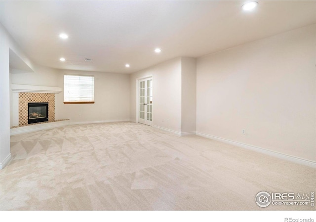 unfurnished living room with visible vents, baseboards, a tiled fireplace, light colored carpet, and recessed lighting