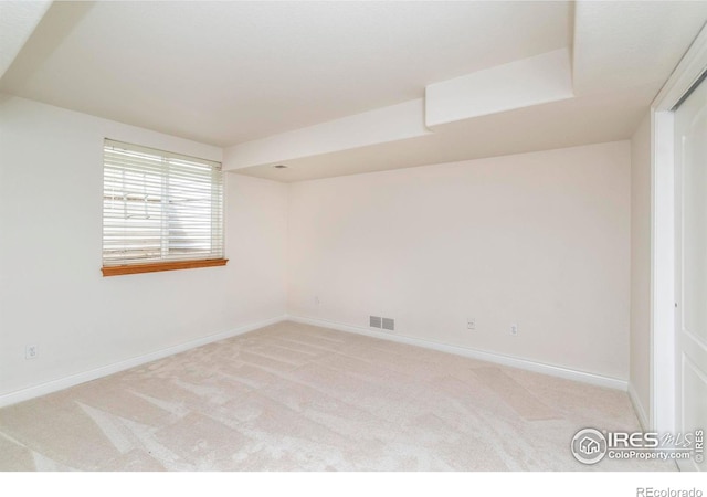 spare room with baseboards, visible vents, and light colored carpet