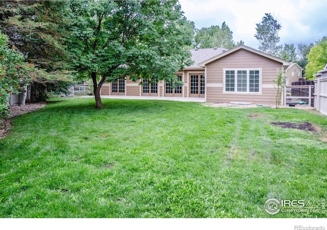 rear view of house with a yard and fence