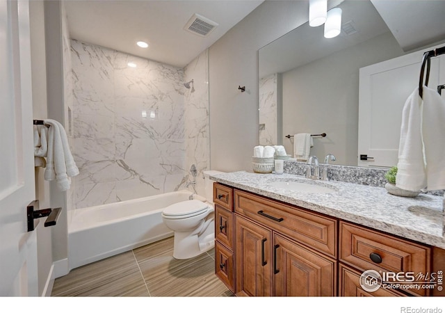 full bathroom with tiled shower / bath, vanity, and toilet