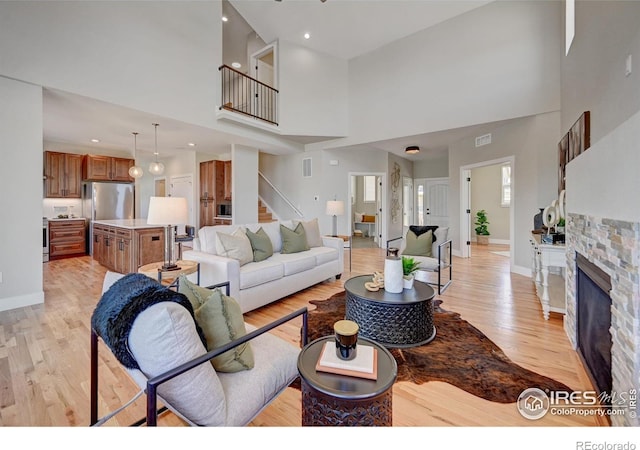 living room with a towering ceiling, a fireplace, and light hardwood / wood-style floors