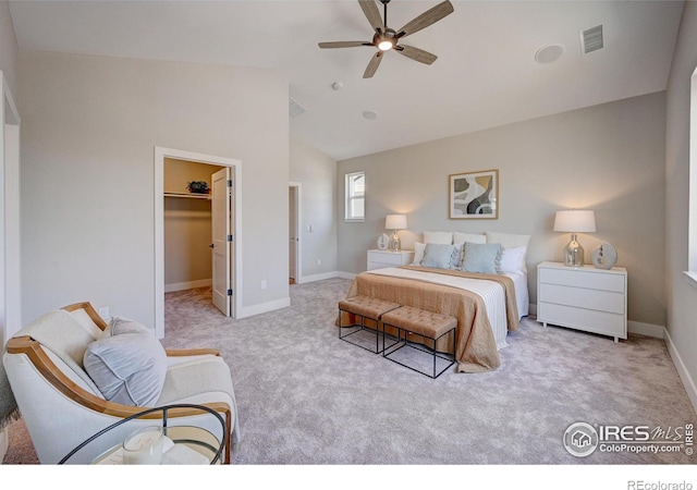 carpeted bedroom featuring vaulted ceiling, a walk in closet, ceiling fan, and a closet