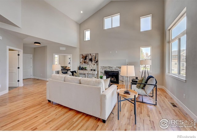 living room with a high ceiling, light wood-type flooring, and a fireplace