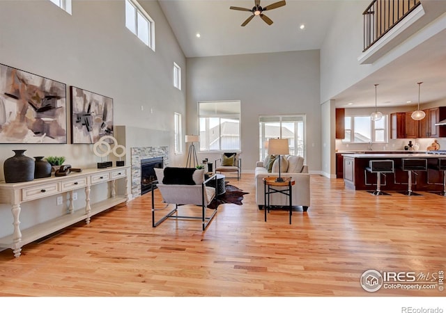 living room with sink, a towering ceiling, ceiling fan, and light wood-type flooring