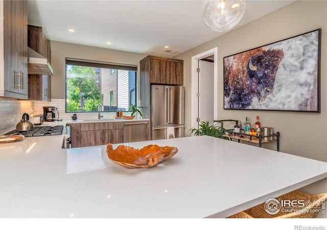 kitchen with sink, backsplash, wall chimney range hood, and stainless steel appliances