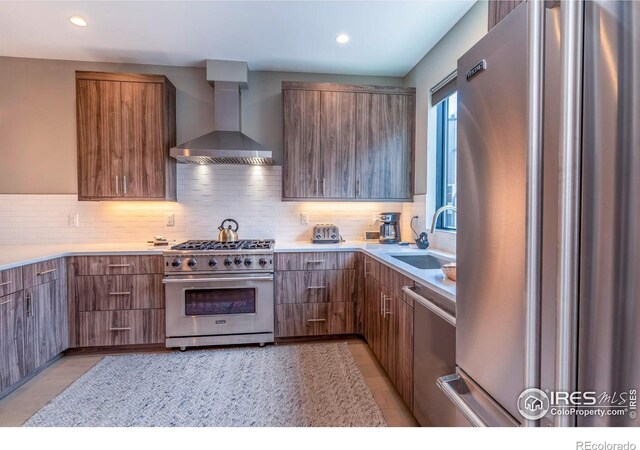 kitchen featuring sink, stainless steel appliances, wall chimney exhaust hood, and tasteful backsplash