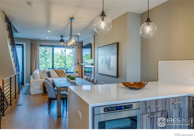 kitchen with stainless steel oven, a chandelier, wood-type flooring, and decorative light fixtures