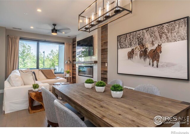 dining space featuring ceiling fan with notable chandelier and wood-type flooring